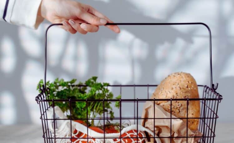 A woman holding a wire basket with groceries inside