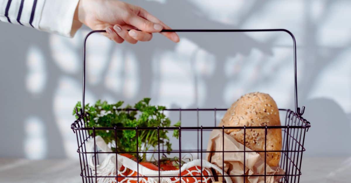 A woman holding a wire basket with groceries inside